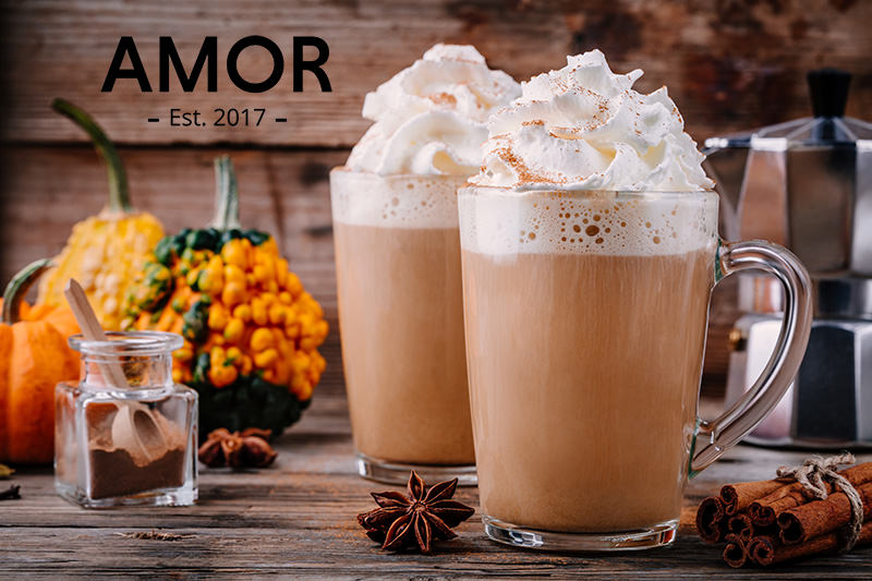 Pumpkin spice drinks topped with whipped cream beside pumpkins and cinnamon